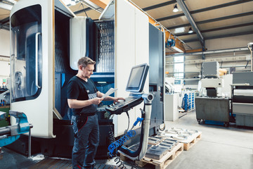 Worker in metal industry operating a modern cnc lathe - 327876870