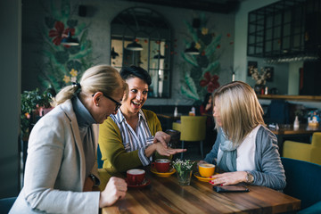 woman showing engagement ring to her friends while drinking coffee in cafeteria
