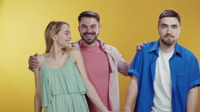 Love triangle. Couple of romantic man and woman standing together isolated. Bearded jealous guy kicking out his friend hugging a girlfriend feel satisfied smile happy. Third wheel concept.