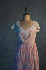 Pink victorian dress on vintage mannequin bust against grey wall.