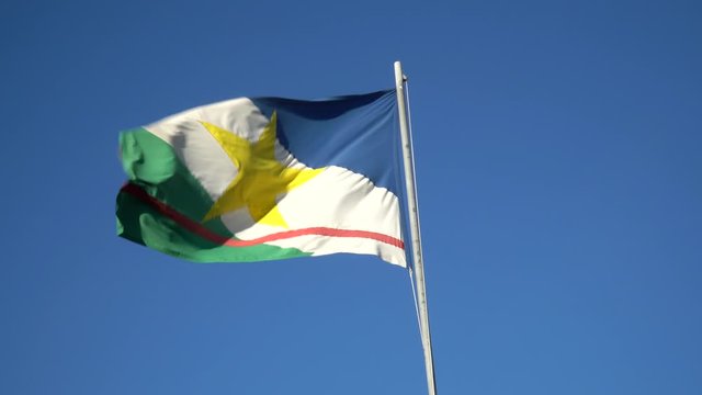 Beautiful flag of Roraima state waving in the wind on sunny summer day with blue sky. Concept of state, symbol, republic, Brazil, cultural identity, democracy, geography and politics.