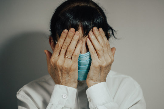 Coronavirus quarantine and Air pollution pm2.5 concept. Sick sad depressed, thoughtful old woman wearing respirator mask for protect. Wuhan, China epidemic virus symptoms background.