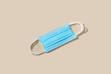 Protective blue face mask on color background. Flat lay