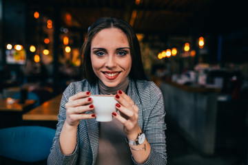 young woman holding cup of coffee at cafe