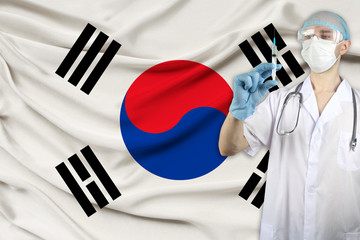 doctor with a stethoscope against the backdrop of the silk national flag of South Korea is holding...