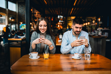man and woman suing mobile phone in cafe