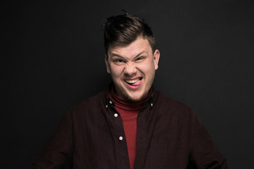 Portrait of young grimacing man isolated on gray background