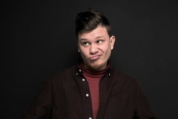 Portrait of young grimacing man isolated on gray background