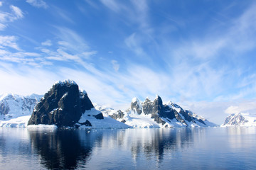 Fototapeta na wymiar Snow-capped mountains and icy coasts at the entrance to the Lemaire Channel in the Antarctic Peninsula, Antarctica