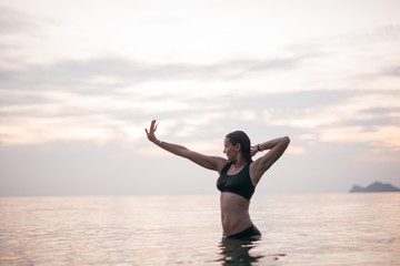 Fototapeta premium A woman enjoys the evening and the ocean at sunset.