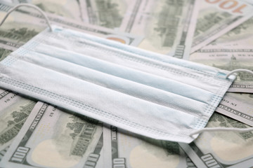 Medical mask on dollars as a symbol of increasing prices for protecting the respiratory tract from the virus. There is a place for copyspace.