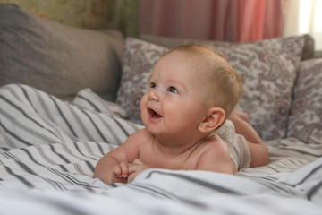 little chubby baby smiling while lying on the bed