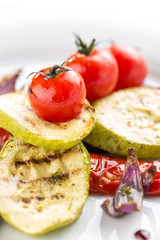 Grilled colorful vegetables aubergines, zucchini, pepper and cherry tomato close up on white background