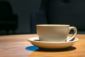 A ceramic cup of cappuccino on a table, close up, no people, profile view.
