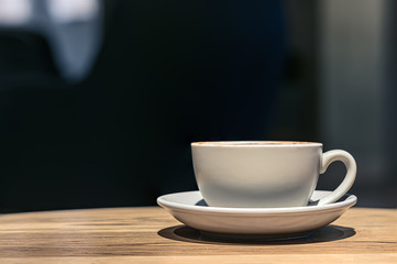 A ceramic cup of cappuccino on a table, close up, no people, profile view.