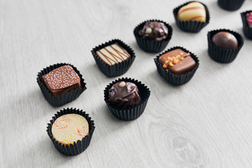 Different chocolate candies on wooden table.