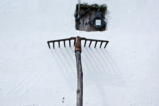 Rustic Rake Leaning Against Old Cottage