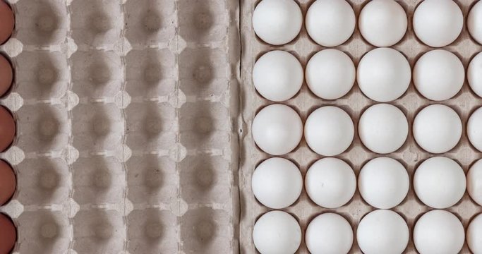 Top view chicken raw eggs of yellow and white color in carton recyclable cardboard box appearing, close-up view on natural pattern, concept of spring and easter