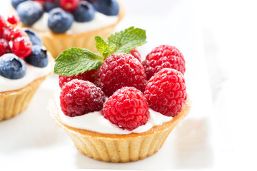 mini cakes with cream and fresh berries, closeup