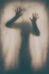 Concept of a frightened woman behind sheet with backlighting in monochrome