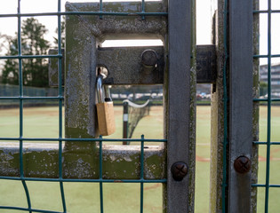 Padlock on gate to tennis courts. The net is visible in the background