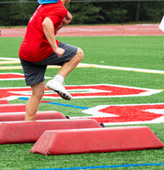 High school football player running sideways over red barriers