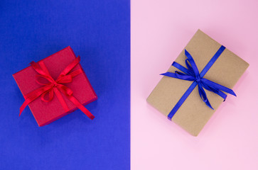 Gift with a blue and red ribbon on a double background. Kraft gift box with blue ribbon. Pink and blue background.