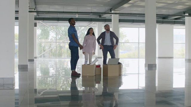Office employees moving to new large office with stuff and equipment, looking around and planning future interior and design
