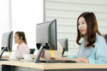 Beautiful smiling call center worker in headphones is working at modern office