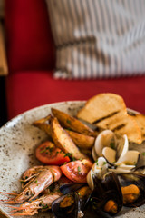 A plate with a variety of seafood stands on a table in a restaurant