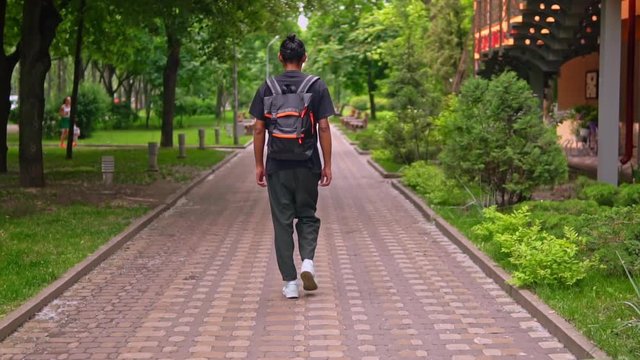 african american man with backpack walking on the street traveller in city slow motion summer nature outdoors