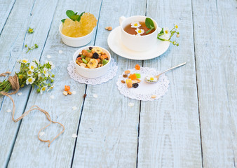 Healthy Herbal Flower tea. Tea cup with wild strawberry Flowers and Candied fruits, dried Fruits, Nuts, Crystal Sugar on wooden table. Herbal Medicine. Phytotherapy Medicinal Herbs