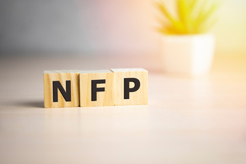 NFP - acronym from wooden blocks with letters, abbreviation NFP Nonfarm Payrolls key economic indicator or Natural Family Planning concept, white background.