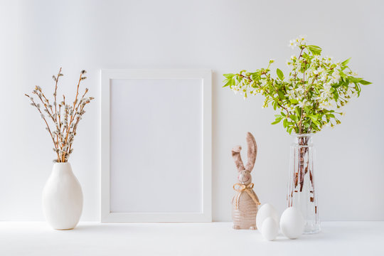 Home interior with easter decor. Mockup with a white frame and spring flowers in a vases on a light background