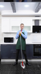 vertical image. handsome man in tie and apron mops the floor in the kitchen
