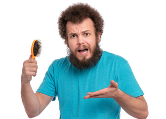 Crazy bearded Man with funny Curly Hair tries to comb his tangled and naughty hair with a small...