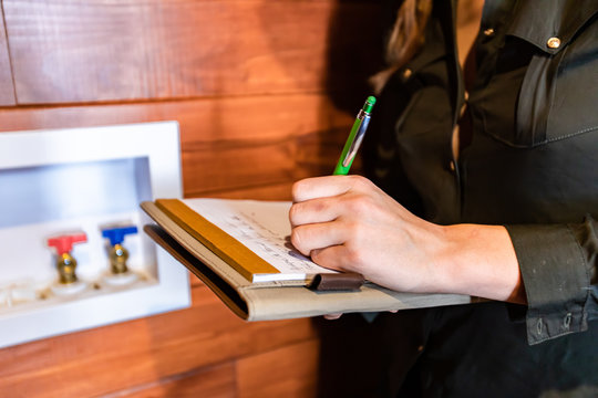 close up on woman's hands as she holding clipboard and takes notes during a house air quality inspection. inspecting modern eco energy efficient home
