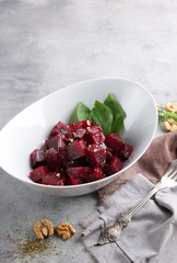 Healthy food. Beetroot salad with olive oil, nuts and herbs in a deep bowl on a light grey background. Background image, copy space