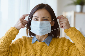 Portrait of young Asian woman,  wearing a medical surgical disposable face mask to prevent...