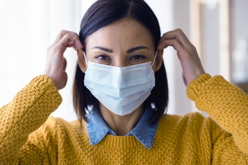 Portrait of young Asian woman,  wearing a medical surgical disposable face mask to prevent...