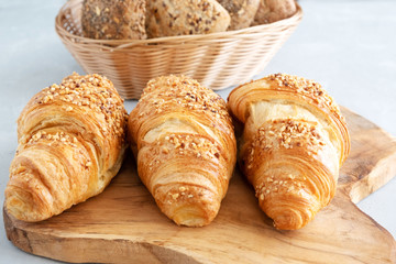 Three fresh traditional french croissants on a wooden board. Close-up. Morning croissants with nuts. Traditional french baking