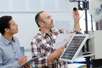 electricians measuring solar panels prior to instalation
