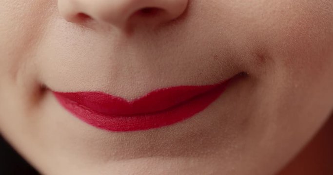 Young female with white teeth applying red lipstick and smiling, glamour