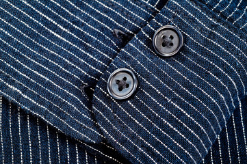 The texture of a denim shirt in dark blue with a small strip on the buttons. Background for fabric and clothes. Fashion, style and practicality.