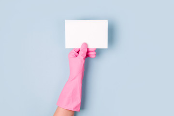 Hands in pink gloves hold empty card. Cleaning or housekeeping concept background. Copy space. Flat lay, Top view.