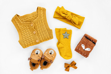 Yellow knitted romper, hairband, socks and cute baby slippers.  Set of newborn clothes and accessories. Flat lay, top view