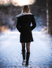 Young Blonde Girl Walking Down a Winter Path Wearing a Winter Coat