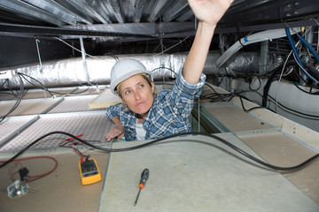 female electrician pulling cables in the ceiling