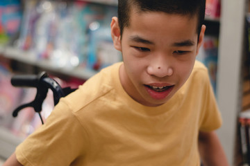 Disabled child on wheelchair having fun choosing books from shelves, Special children's lifestyle, Life in the education age of special need kids, Happy disability kid concept, Selective focus.