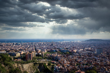 Fototapeta na wymiar Panorama of Barcelona, Spain, viewed from the Bunkers of Carmel on a cloudy day with rays of light. Aerial top view from hill with modern buildings.